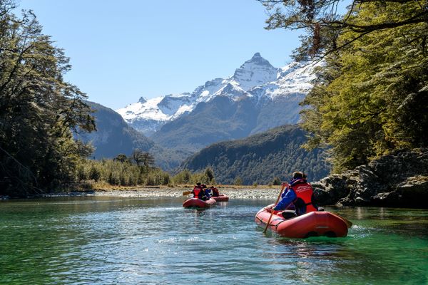 Dart River Adventures Funyaks paddling through the water with mountain views in the background